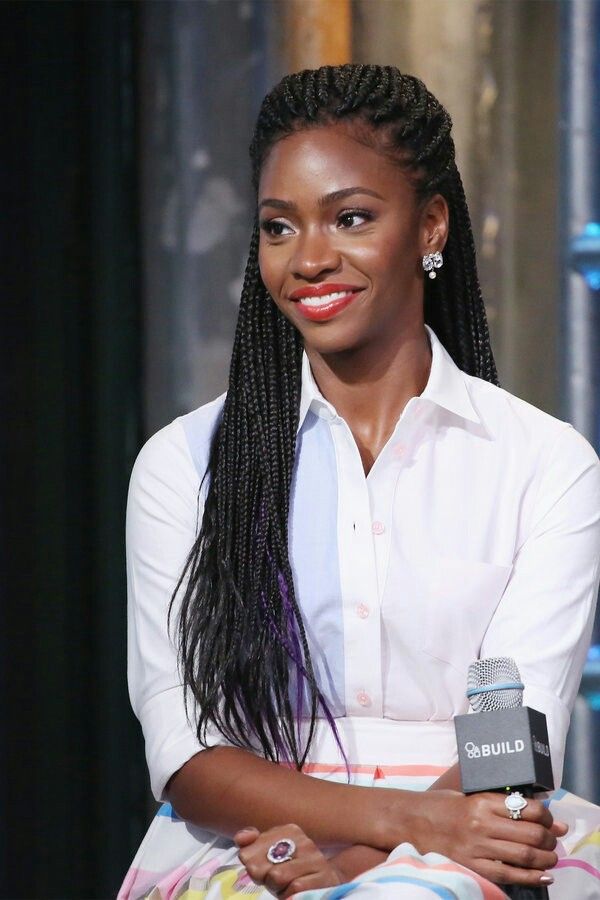 Women with braided hair sitting on stage with microphone smiling