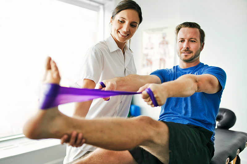 Fizjoterapia w czasie treningów kolarskich. Fizjoterapeuta wykonuje zabieg z pacjentem.