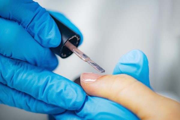 Kosmetyczka nakładająca odżywkę na paznokcie
